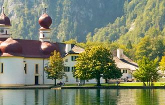 Ein See mit Bäumen und Bergen.