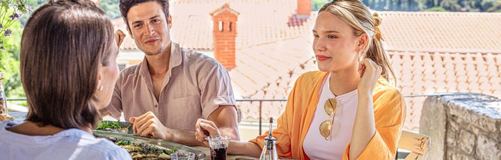 Drei Menschen beim Essen mit Wasser im Hintergrund