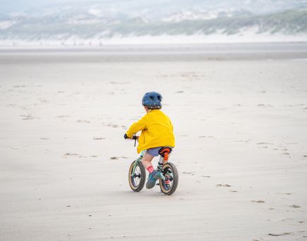 Kind auf Laufrad, Sandstrand in Hardelot, Frankreich