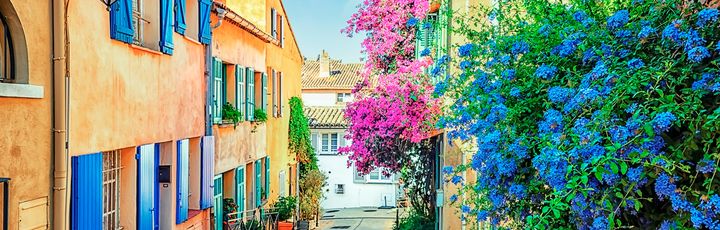 Schmale Gasse mit bunten Häusern und bunten Blumen, blaue Fensterläden