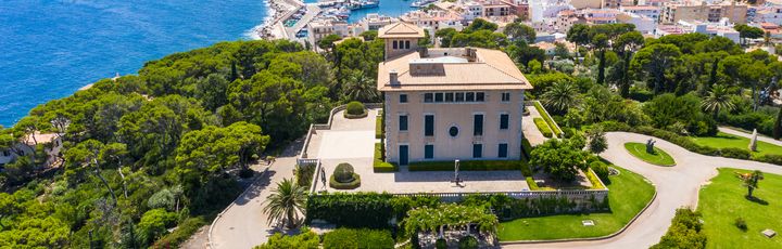 Blick auf die Villa March, umgeben von saftiger Wiese und blauem Himmel.