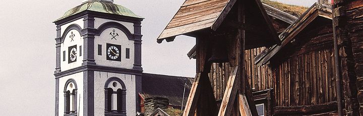 Eine alte, traditionelle Stabkirche in Norwegen, umgeben von grüner Vegetation.
