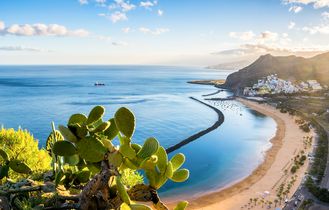 Eine Küstenlandschaft mit einem Strand, Bergen und einer Stadt.