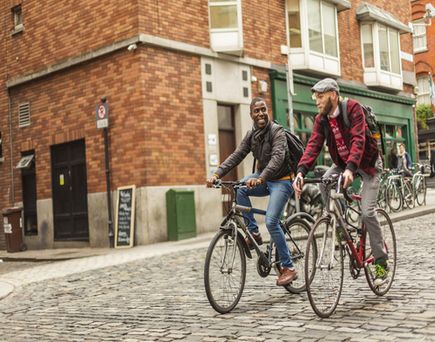 Zwei Personen fahren Fahrrad auf einer Straße.