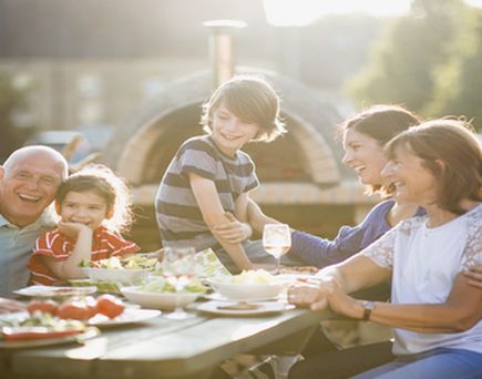 Eine Familie sitzt an einem Tisch im Freien und isst.