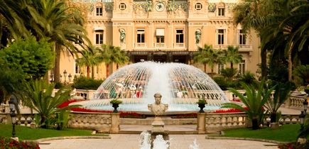 Ein prunkvolles historisches Gebäude mit einem Brunnen und einem gepflegten Garten. Die Architektur ist symmetrisch und beeindruckend.