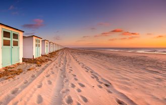 Ein Strand mit kleinen Strandhütten und einem Weg.
