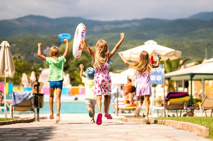 Kinder laufen mit Schwimmutensilien richtung pool