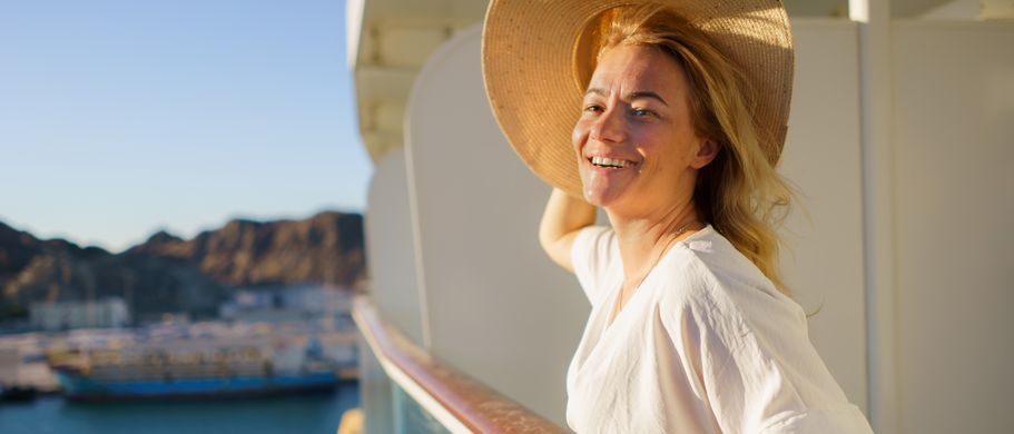 Frau steht an Reeling von Kreuzfahrtschiff