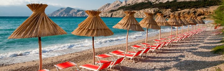 Ein Strand mit Sonnenschirmen und Liegestühlen.