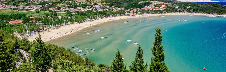 Ein Sandstrand mit türkisblauem Wasser.
