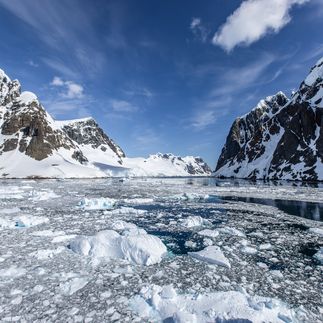Ein Schiff fährt durch einen engen Kanal mit hohen, eisbedeckten Klippen.