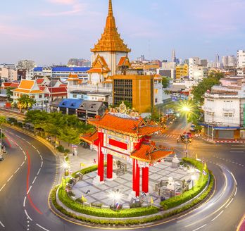 Das hell erleuchtete chinesische Tor am Odeon Circle in Bangkoks Stadtteil Chinatown bei Dämmerung.