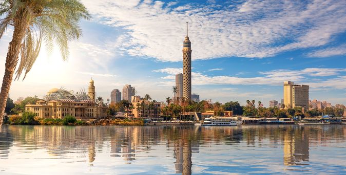 Die Skyline von Kairo mit dem Fernsehturm spiegelt sich an einem sonnigen Tag im ruhigen Wasser des Nils.