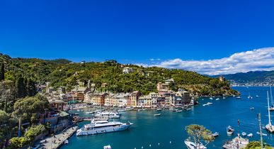 Luftaufnahme der malerischen Hafenstadt Portofino in Ligurien, Italien, mit bunten Häusern und Yachten im klaren Wasser.