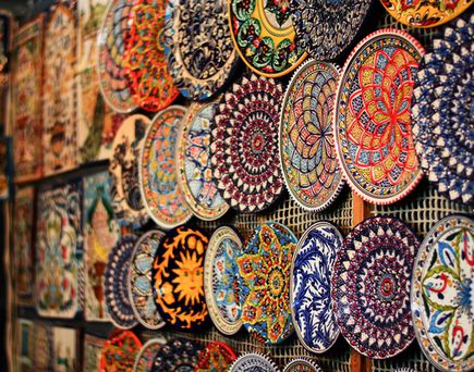Detailreich bemalte Keramikteller in leuchtenden Farben schmücken die Wand eines kunstvollen orientalischen Marktes.