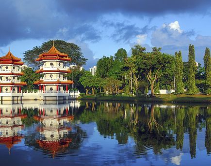 Ein prächtiger chinesischer Garten mit traditioneller Architektur, einer roten Brücke über einem Teich und üppiger Vegetation.