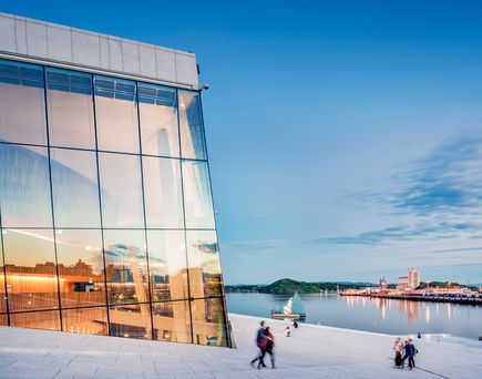 Modernes, architektonisch anspruchsvolles Gebäude am Fjordufer in Norwegen unter blauem Himmel.