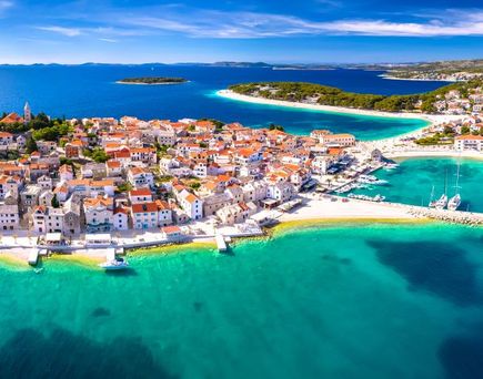 Eine Luftaufnahme einer Küstenstadt mit einer Insel und Booten.