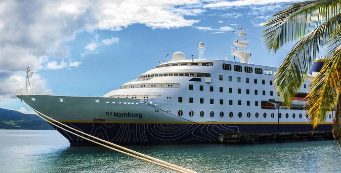 Ein großes Kreuzfahrtschiff auf dem Wasser unter einem blauen Himmel.