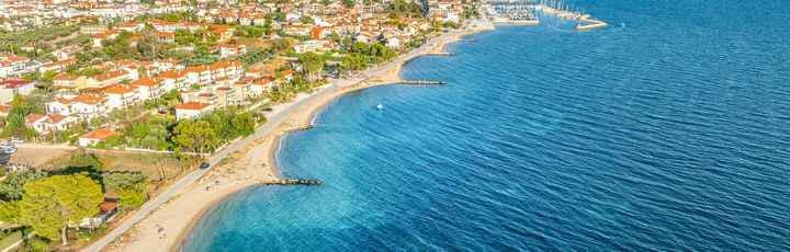 Blick auf Nikiti aus der Vogelperspektive. Strand, grüne Vegetation und einige Häuser.