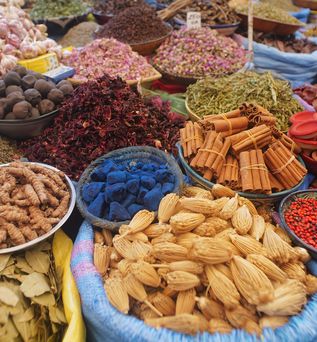 Verschiedene Gewürze und Trockenfrüchte auf einem Marktstand.
