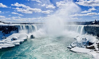 Die Niagara Fälle stürzen mit großer Kraft herab, mit einem Boot im Vordergrund.
