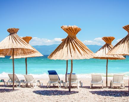 Kroatien Inseln Urlaub Strand mit Schirmen und Liegestühlen