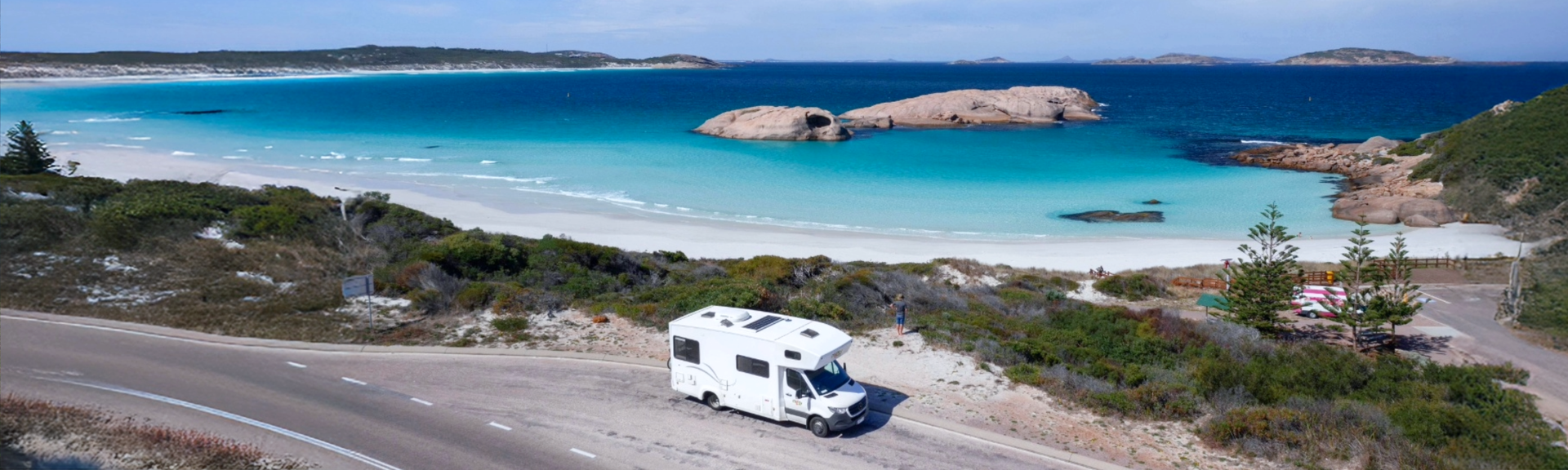 Camper steht an einer Küstenstraße in Australien am hellblauen Meer 
