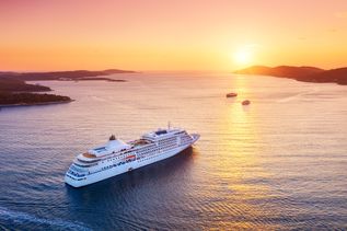 Kreuzfahrtschiff auf offenem Meer fährt in den Sonnenuntergan