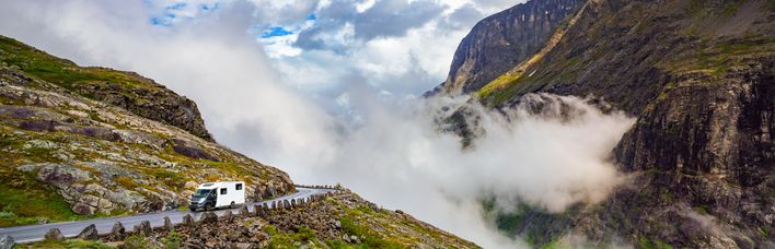 Grünes Tal mit Fluss und sprudelnden Wasserfällen in Norwegen, umgeben von hohen Bergen.