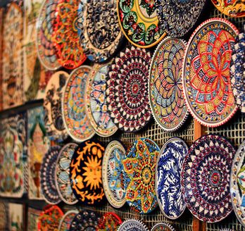 Detailreich bemalte Keramikteller in leuchtenden Farben schmücken die Wand eines kunstvollen orientalischen Marktes.