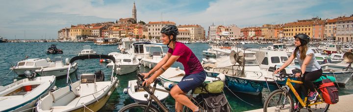 Zwei Frauen fahren Fahrrad am Meer.