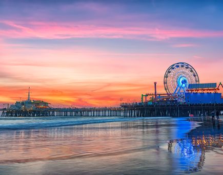 Ein Riesenrad am Strand bei Sonnenuntergang, mit Blick auf das Meer.