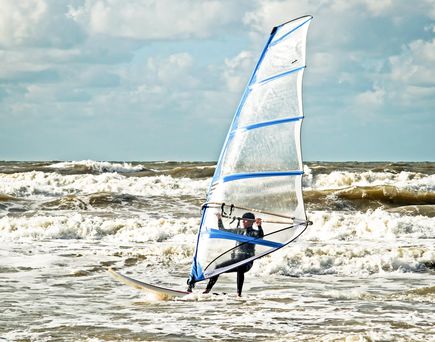 Eine Person auf einem Segelbrett, das auf dem Meer fährt.