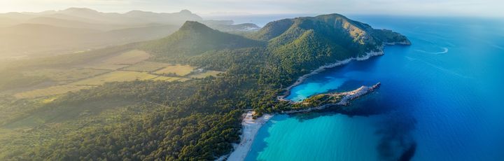 Blick über die Bucht Cala Agulla mit seinem saftig grünem Hinterland.