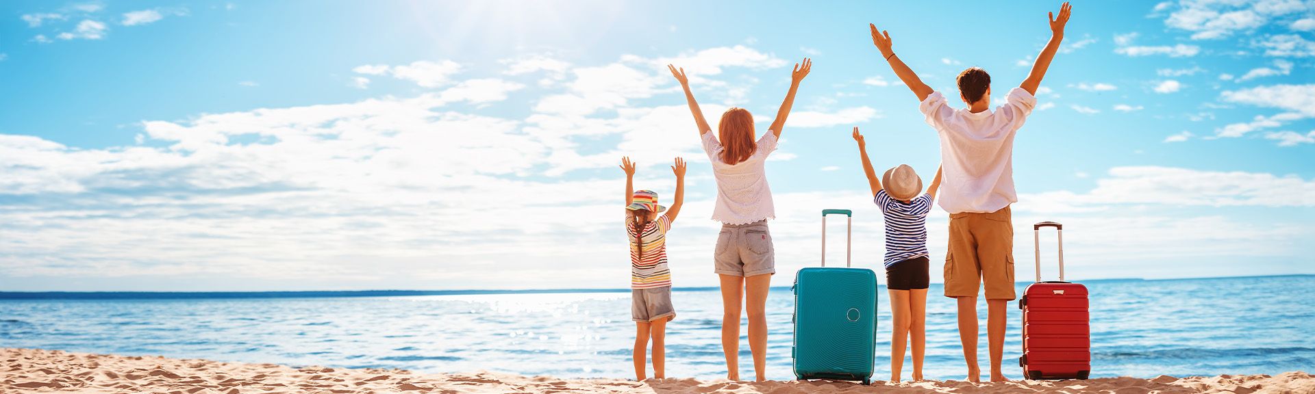 Familie am Strand mit Koffern 