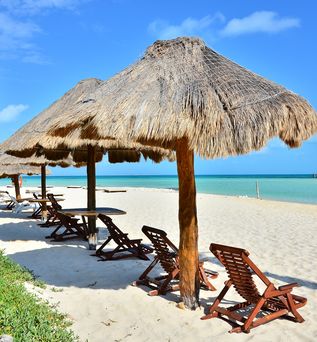 Holzsonnenstühle und Schirme am weißen Strand von Mexiko