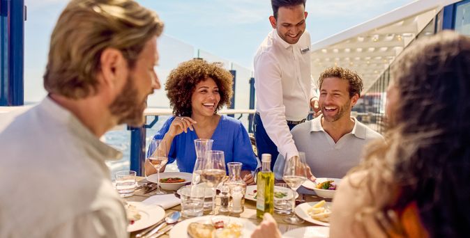 Zwei Paare sitzen am Tisch beim Essen auf dem Schiff