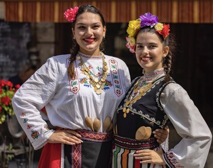Zwei Frauen in traditionellen bulgarischen Trachten posieren für ein Foto.