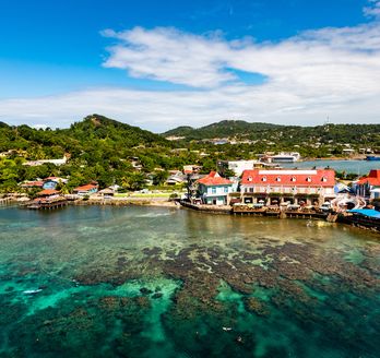 Blick auf die Paradiesische Küste von Roatan, Honduras mit bunten Häusern am Hafen