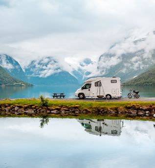 Ein See mit Kanus und einem Zelt, umgeben von Bergen.